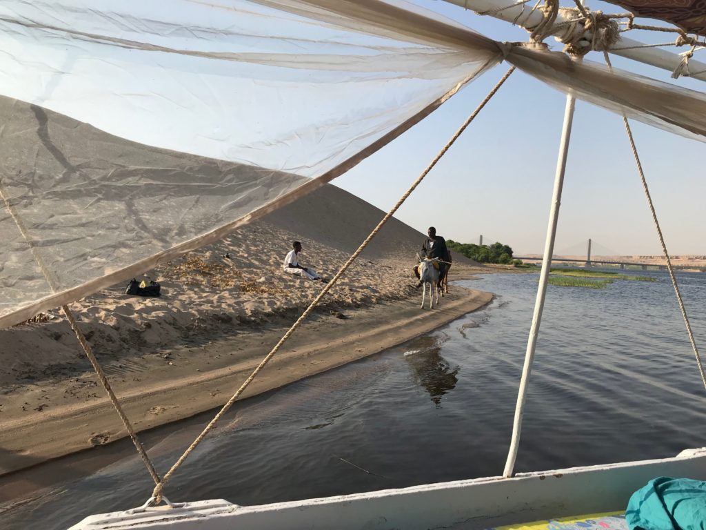 Framing can be used in landscape travel photography to bring more interest, like this cow and people framed by felucca parts on the Nile River in Egypt.