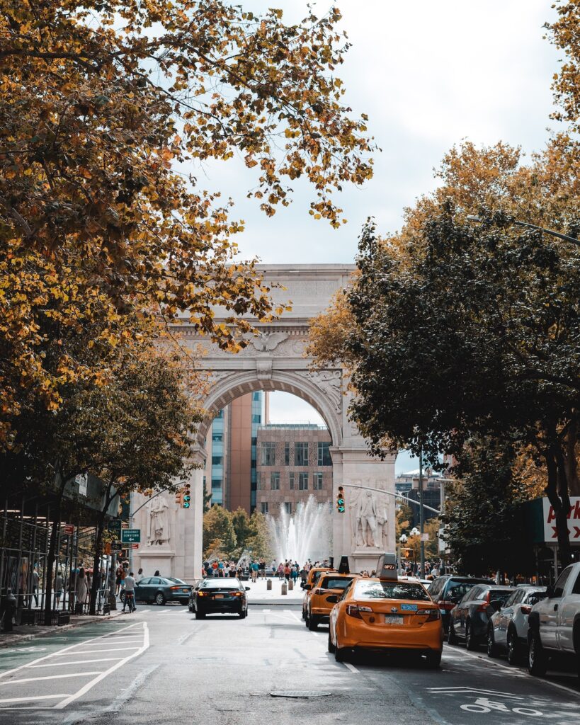 Greenwich Village NYC, Washington Square Park arch in the fall with fountain, taxis, and colorful trees