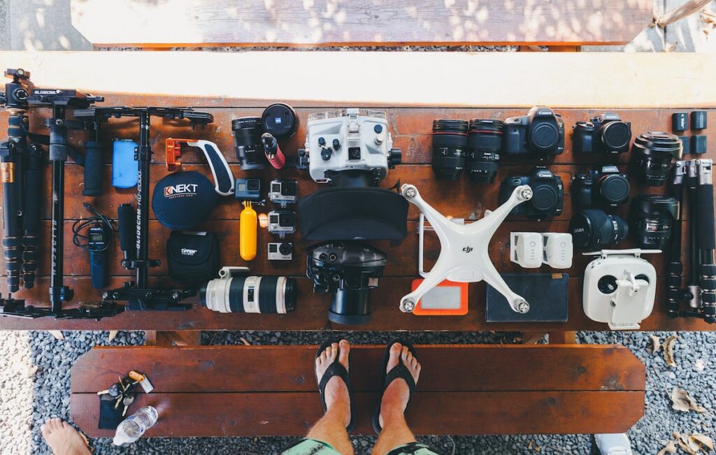 A flat lay photo of cameras and gear, including a drone, lenses and more accessories
